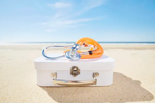 Reiseapotheke mit Stethoskop am Strand