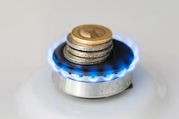 Euro-Münzen auf einem brennenden Gasherd symbolisieren Gaskosten