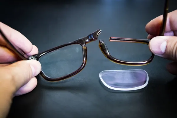Hände mit gebrochener Brille