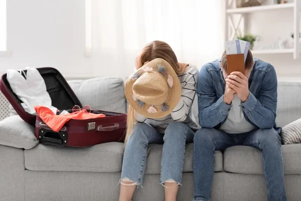Enttäuschtes Paar mit Koffer und Reisepässen