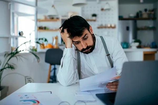 Mann mit Kündigungsunterlagen vor Laptop
