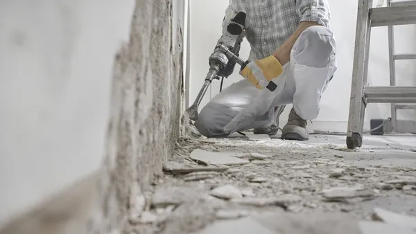 Bauarbeiter bricht die Wand mit dem Hammer