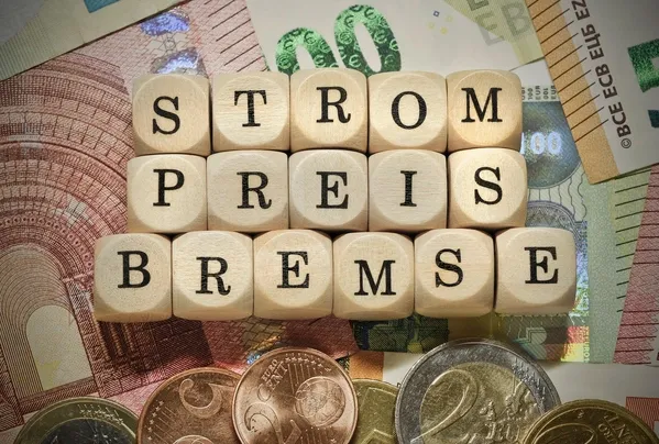 Wort "Strompreisbremse" auf Banknoten und Münzen