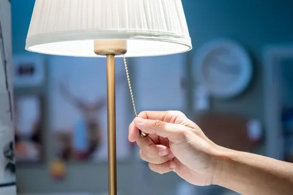 Person zieht an Lichtschalterkette auf Lampe 