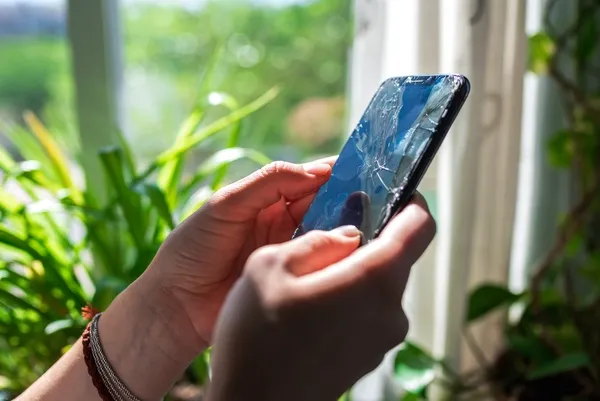 Person hält Handy mit kaputtem Display in der Hand