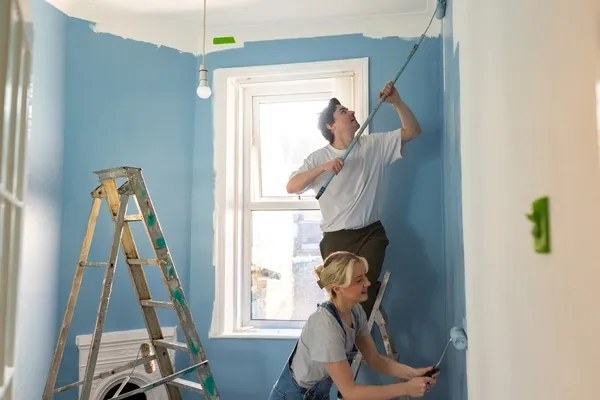 Mann und Frau streichen Wand blau