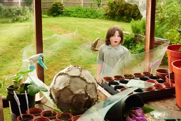 Kind zerbricht Fensterscheibe mit Ball
