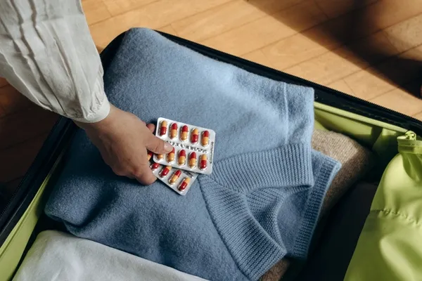Person packt Medikamente in einen Koffer.