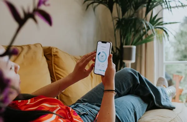 Frau mit Handy schaut sich Stromverbrauch an