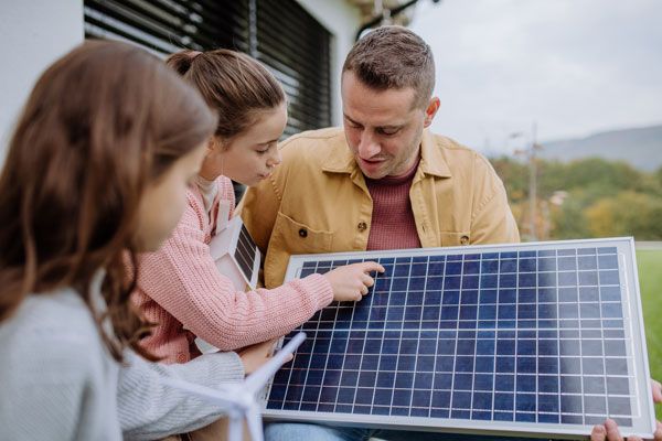 Mädchen und Mann inspizieren Solarmodul
