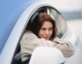 Frau lehnt sich aus einem Autofenster