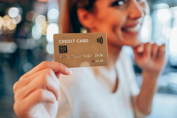 lächelnde Frau hält Kreditkarte in der Hand