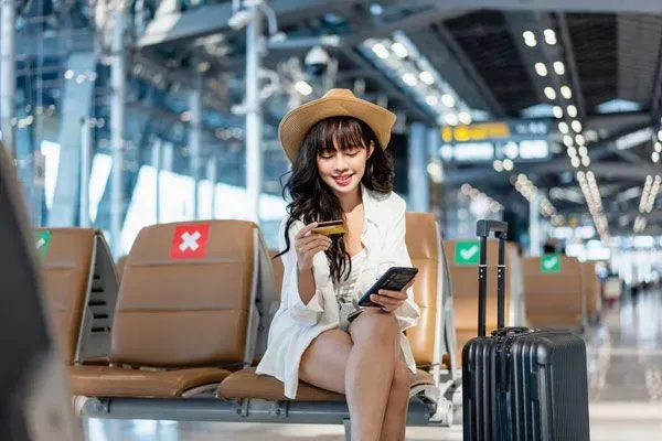 Frau am Flughafen mit Kreditkarte in der Hand
