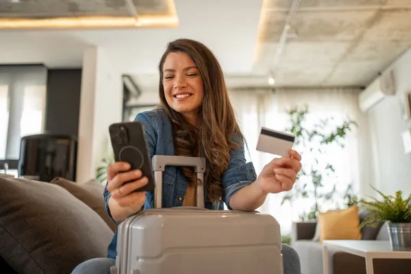 Frau plant eine Reise mit Smartphone und Kreditkarte.