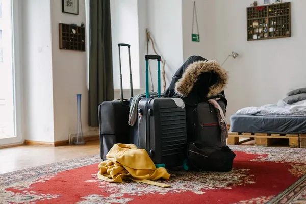 Gepackte Koffer und Kleidung in einem Schlafzimmer.