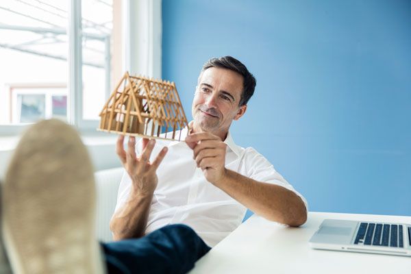 Mann inspiziert Holzmodell eines Hauses