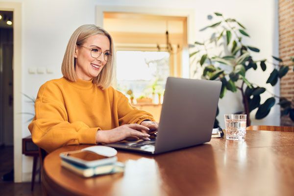 Frau schickt mit Laptop Unterlagen für Baufinanzierung